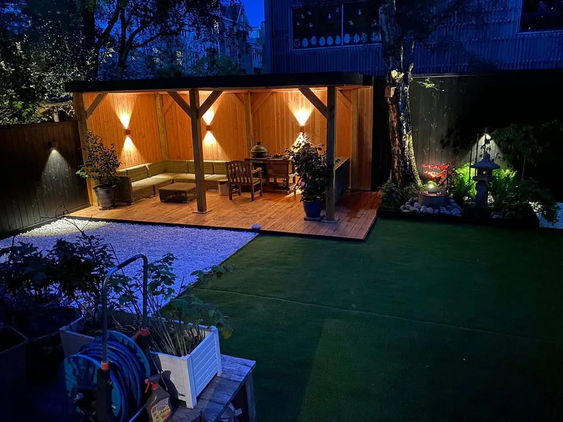 Sfeervol verlichte tuin met overkapping in de avond